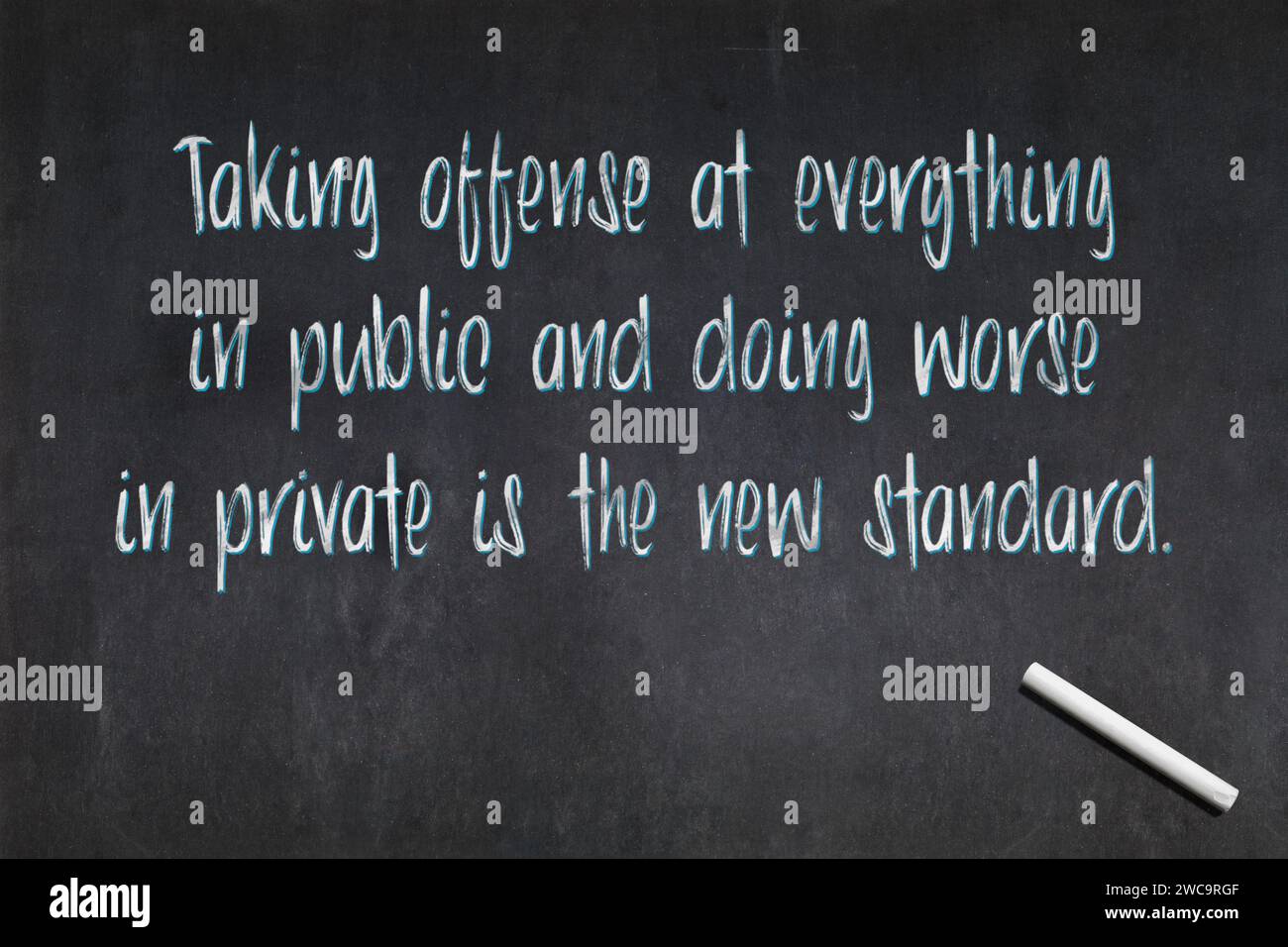 Blackboard with a quote saying 'Taking offense at everything in public and doing worse in private is the new standard.', drawn in the middle. Stock Photo