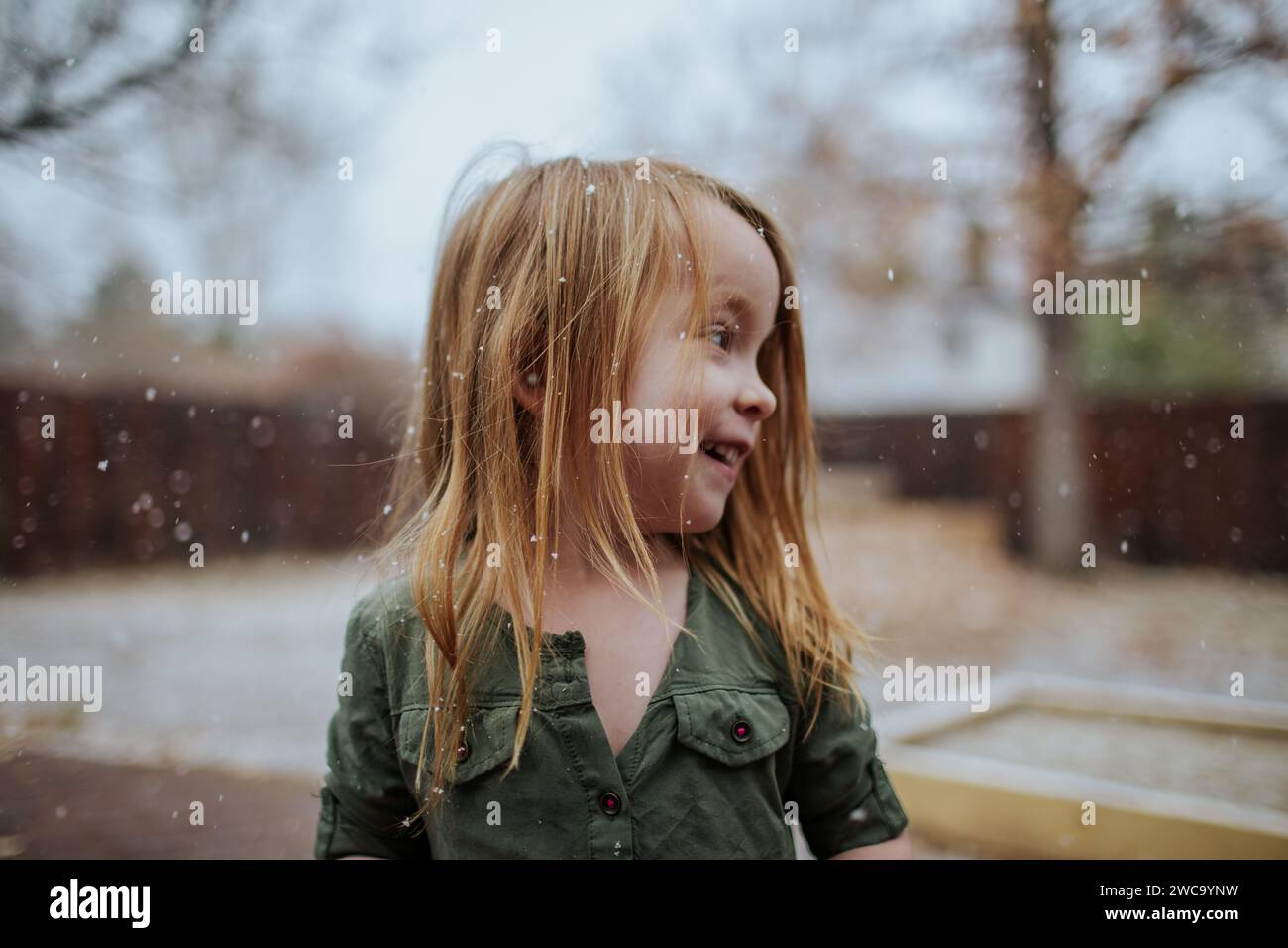 Happy preschool girl standing outside in light snow Stock Photo