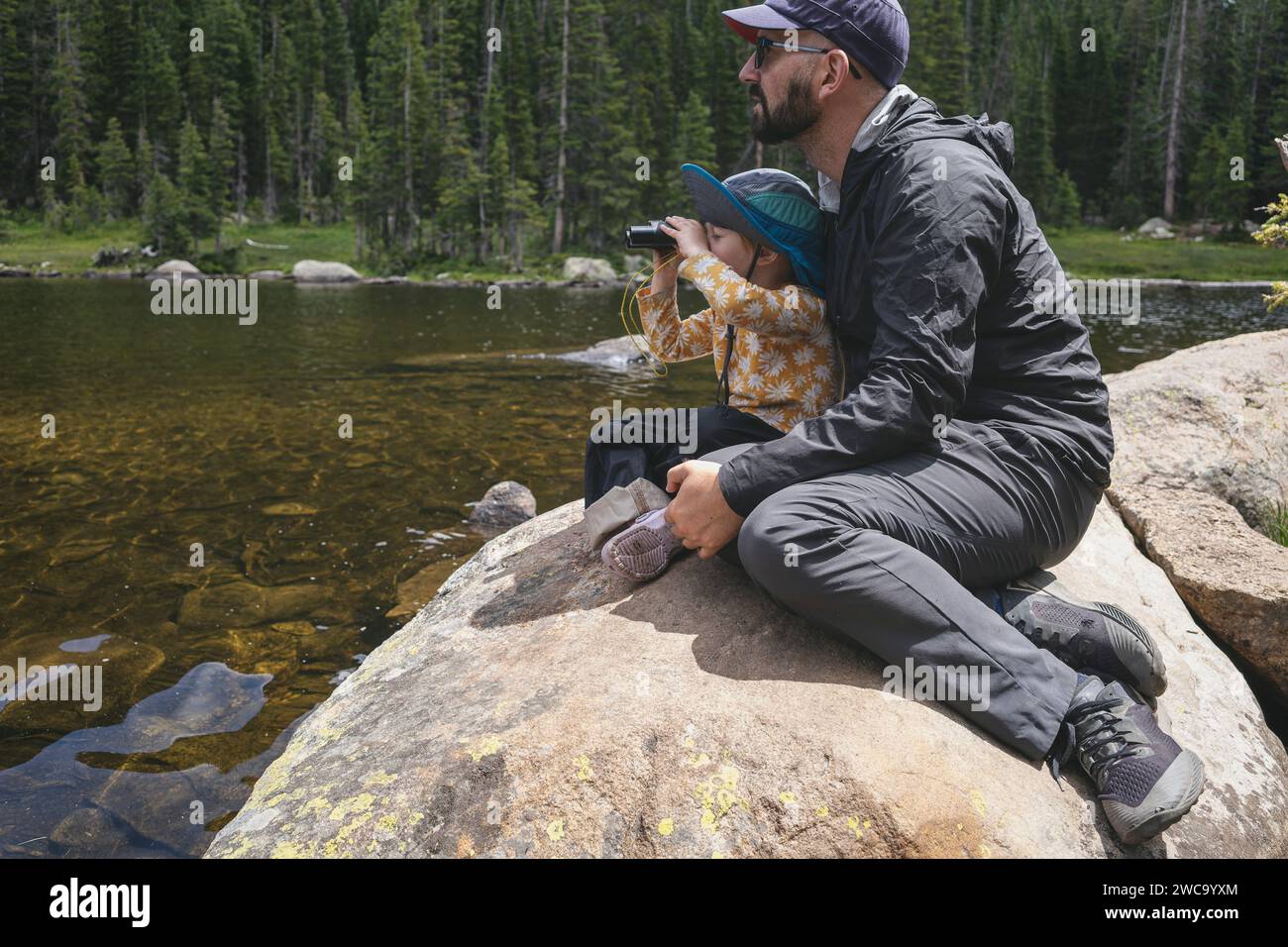 Father and child enjoying nature by a mountain lake Stock Photo