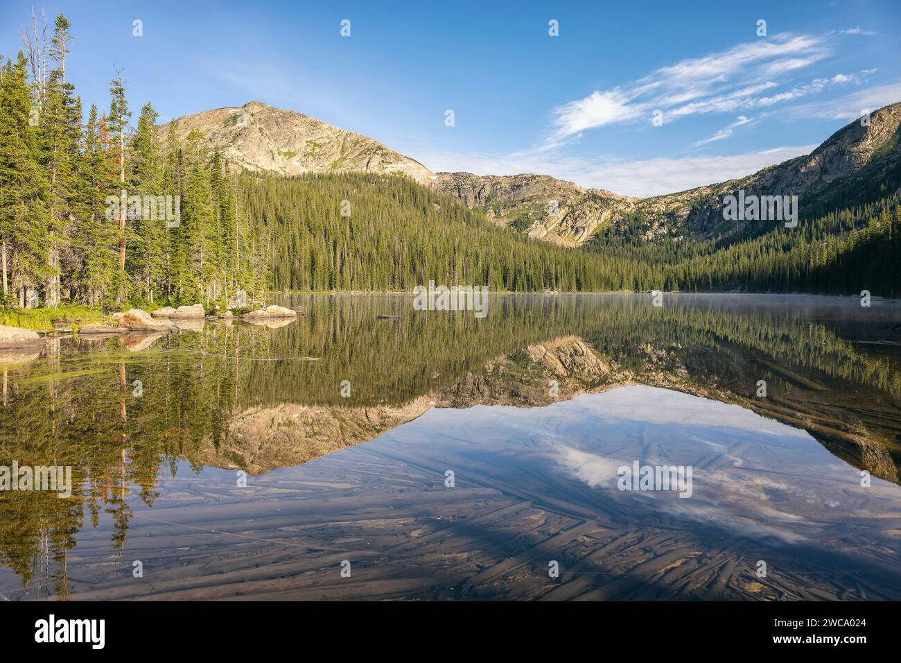 Tranquil mountain lake reflecting blue sky and forest Stock Photo