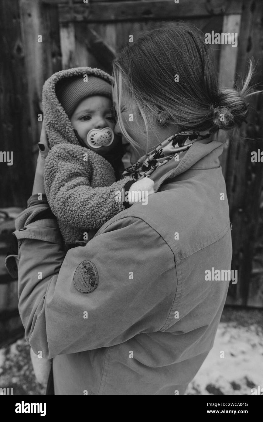 Mom cuddles baby after a snowy horseback ride Stock Photo