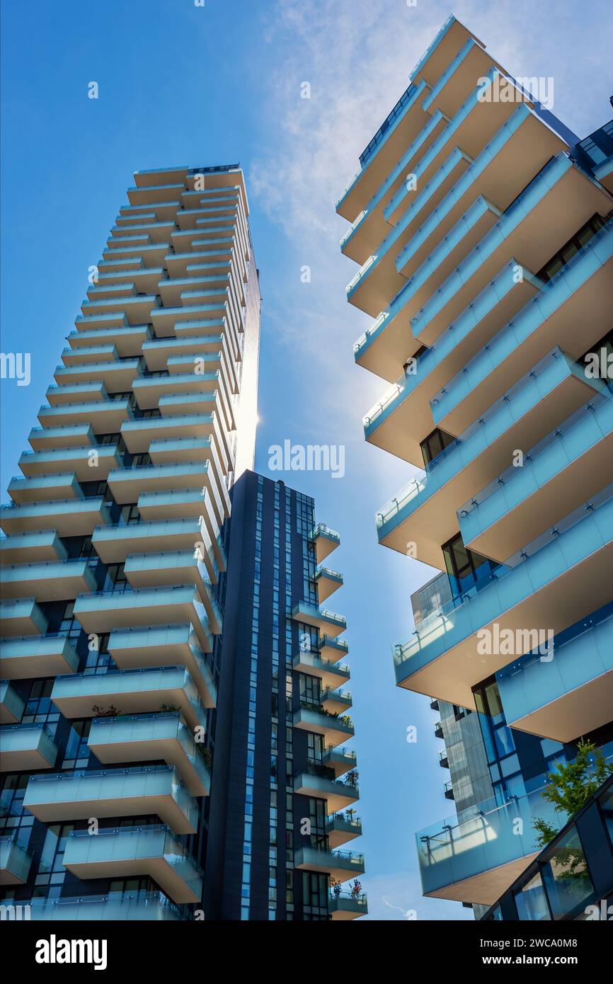 From below exterior of multistory residential skyscrapers located in Milan Italy Europe in sunny daylight against blue sky with clouds Stock Photo