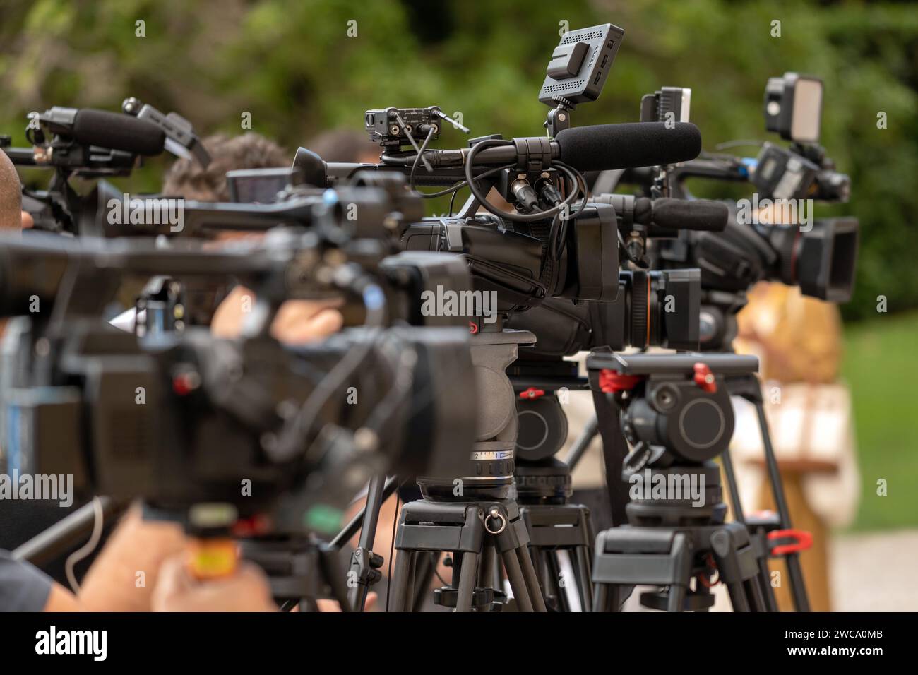 Modern professional video cameras placed on tripods against blurred background of nature during business conference in summer Stock Photo