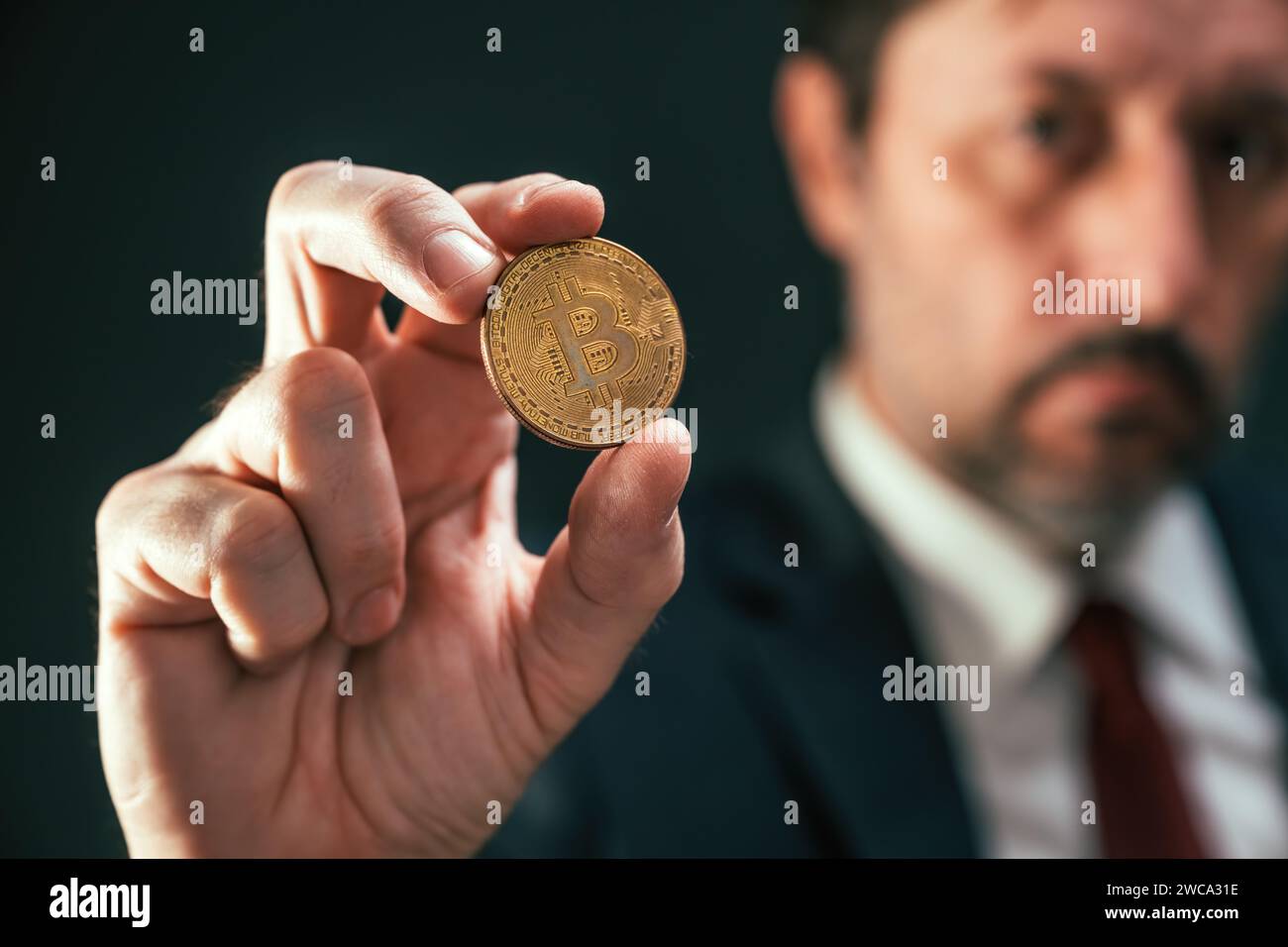 Cryptocurrency trader holding Bitcoin coin in hand Stock Photo