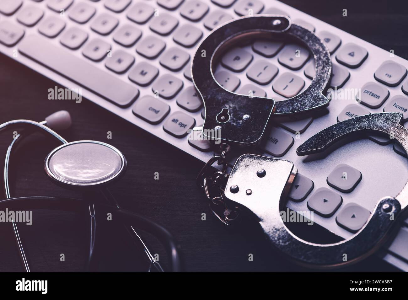 Stethoscope handcuffs and computer keyboard. Criminal activity in healthcare industry concept. Selective focus. Stock Photo