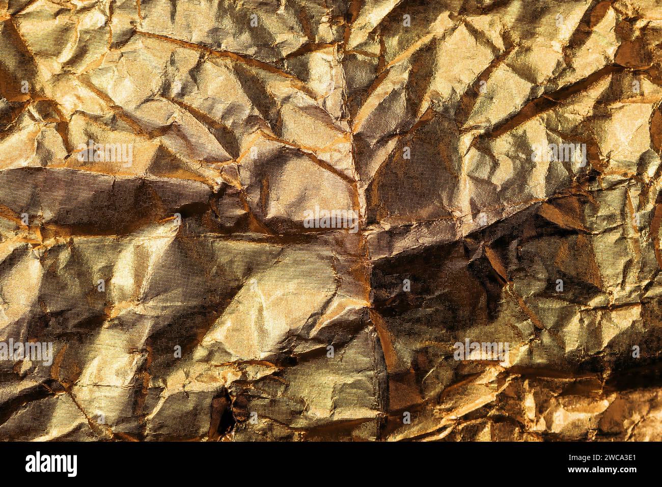 Crumpled gold colored aluminum tin foil texture as background, top view Stock Photo