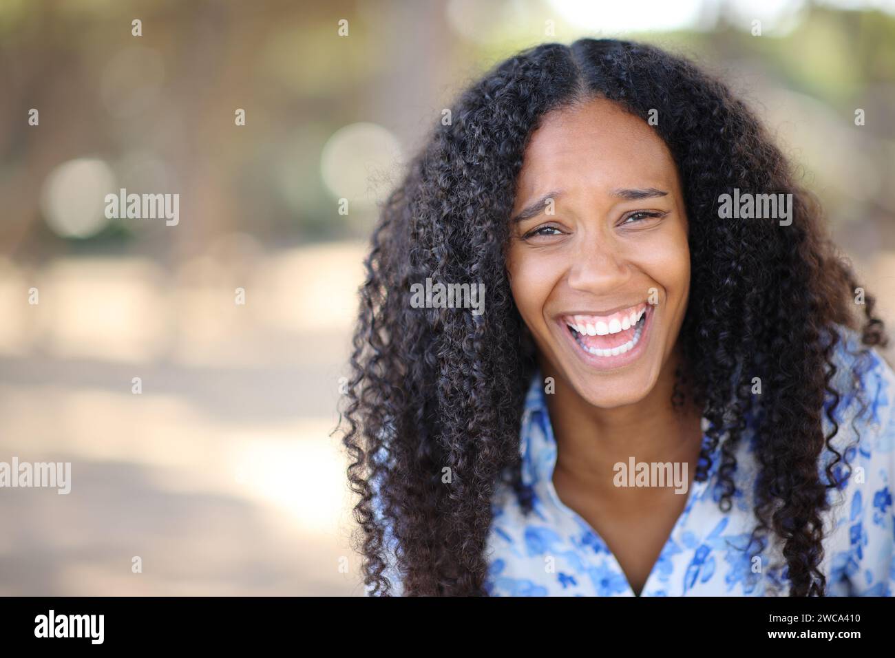 Front view portrait of a funny black woman laughing looking at you in a park Stock Photo