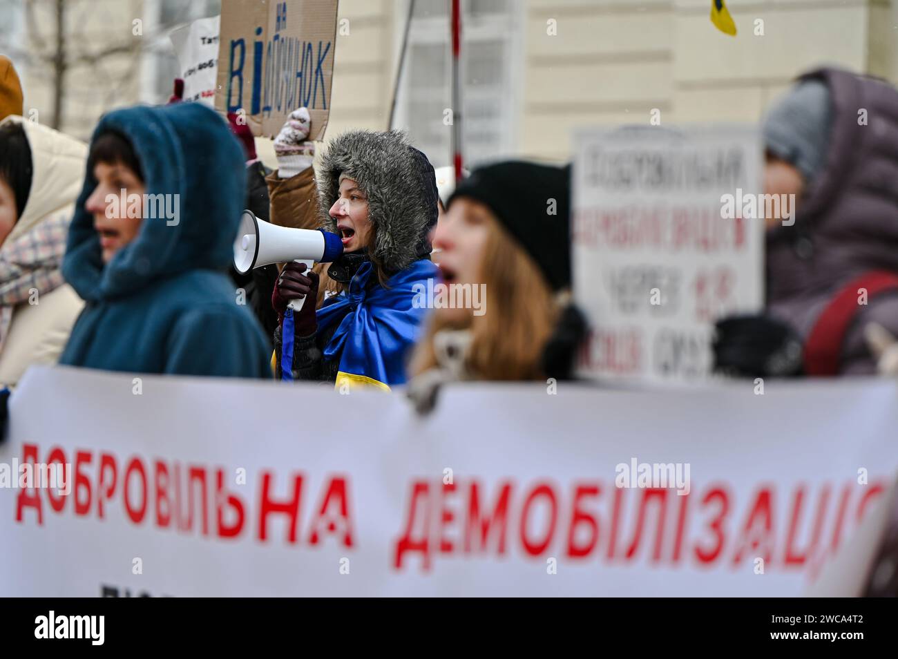 LVIV, UKRAINE - JANUARY 14, 2024 - A woman with a megaphone is seen during the rally of wives and relatives of Ukrainian soldiers to demand the authorities pass a law that would give defenders the right to demobilize after 18 months of service, outside the Lviv City Council , Lviv, western Ukraine. Stock Photo