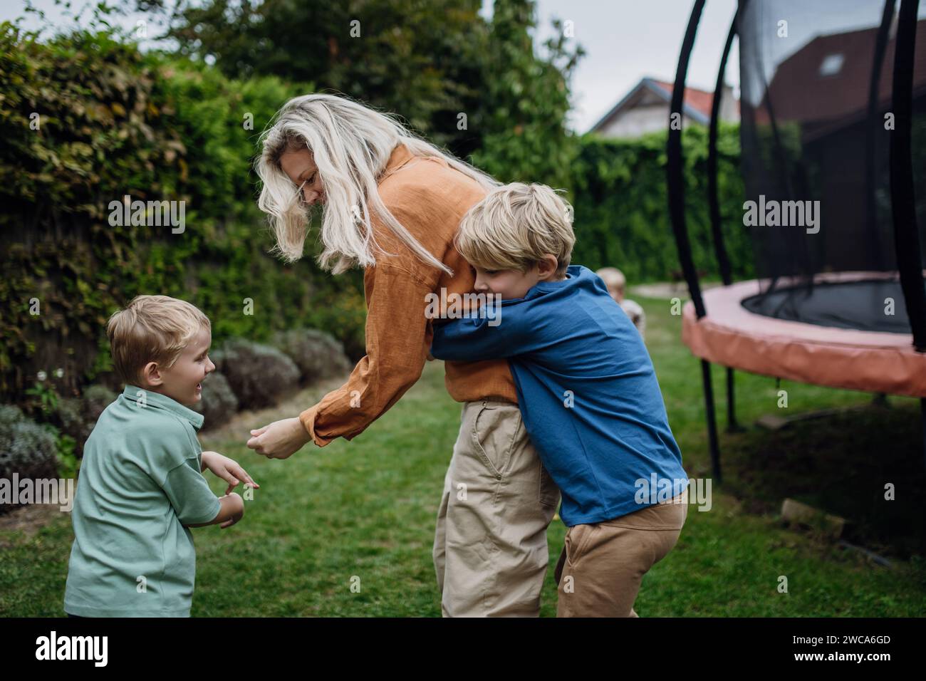 Mother having fun with sons in the garden, bonding moment. Concept of Mother's Day, and motherly love. Stock Photo