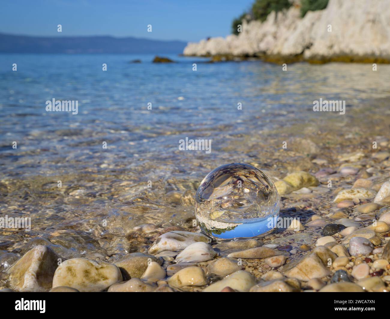 Glass ball lying in the water at the beach, sunny day in autumn in Cres ...