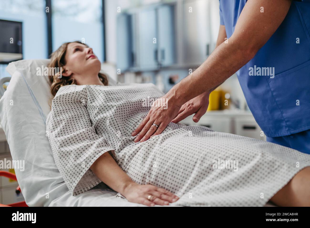 Doctor palpating woman's abdomen, using hands and steady pressure Stock