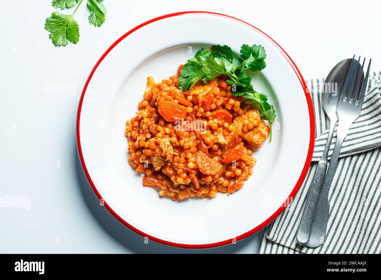 Ptitim with chicken, vegetables and cilantro, white background, top view. Traditional Israeli food. Stock Photo
