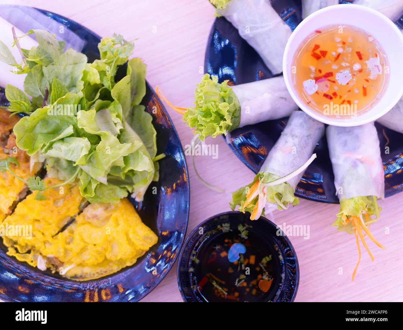 Two Vietnamese dishes, banh xeo and goi cuon (spring rolls) with condiments at a restaurant in Thanh Hoa, Vietnam. Shallow depth of field with the spr Stock Photo