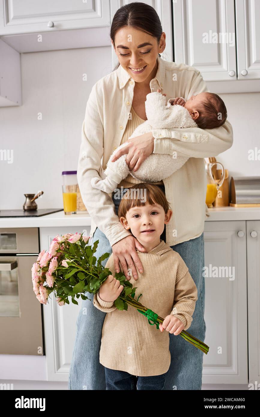 caring cheerful family in housewear posing with flower bouquet while on kitchen, modern parenting Stock Photo