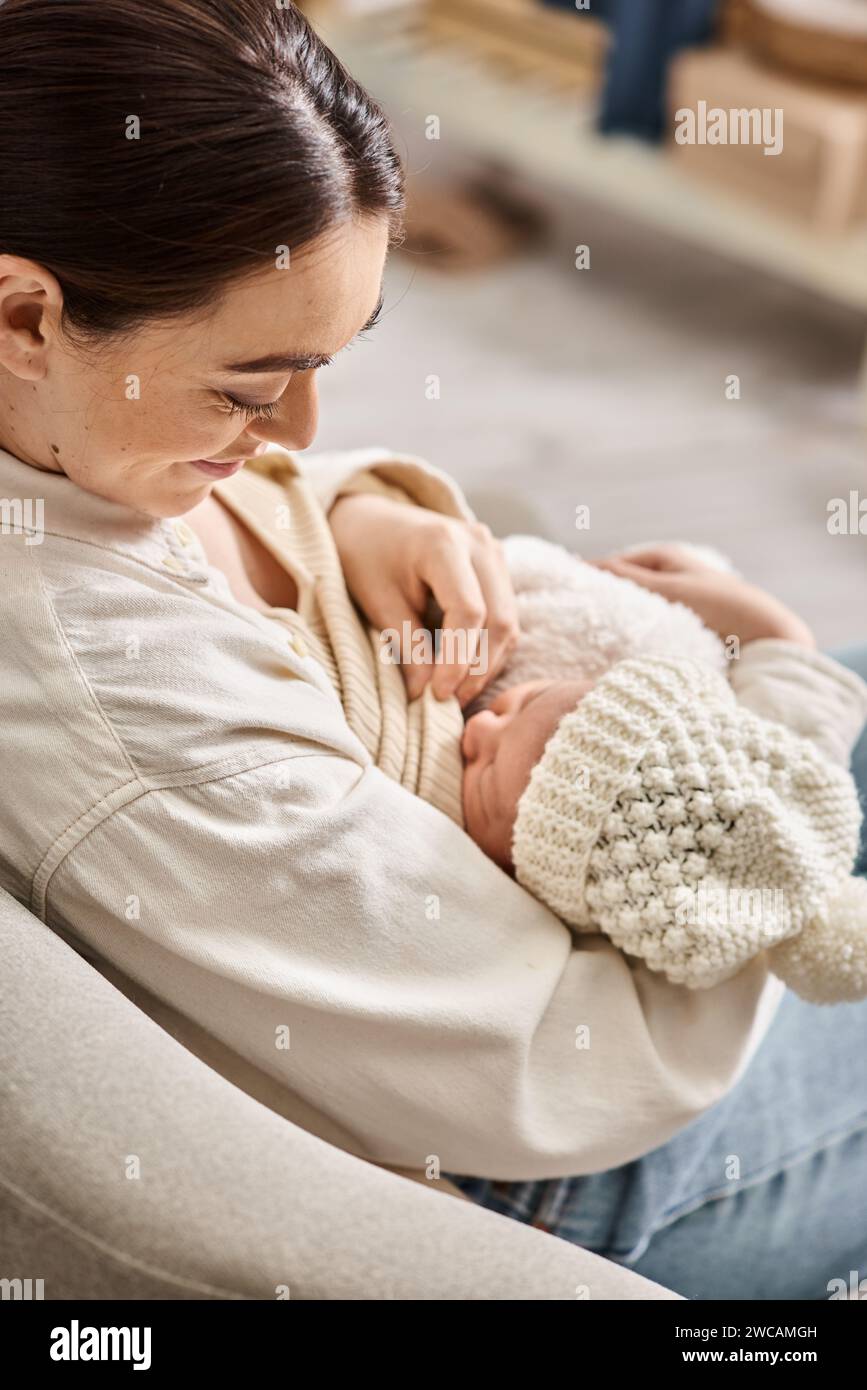 beautiful woman in cozy casual attire breastfeeding her cute newborn child, modern parenting Stock Photo