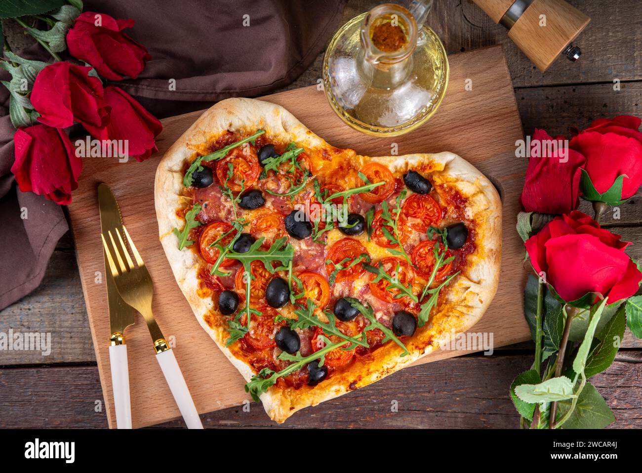 Valentines day heart shaped pizza, love and dating concept with mozzarella. tomatoes, pepperoni and arugula on vintage wooden table background top vie Stock Photo