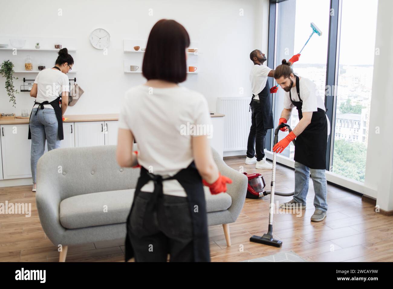 Group of janitors in uniform cleaning office with cleaning equipment. Stock Photo