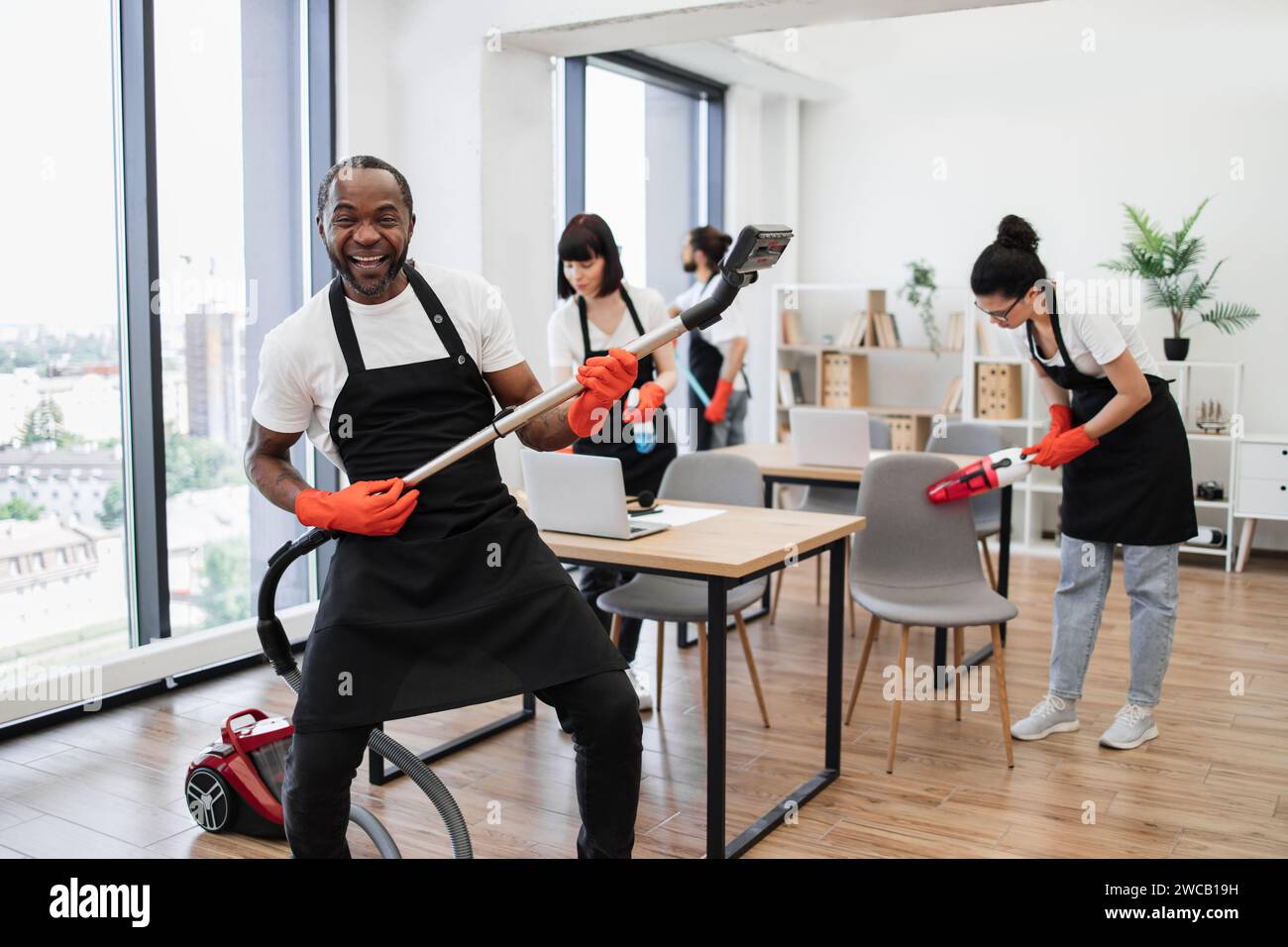 Happy multinational team of people in black aprons cleaning modern office Stock Photo Alamy