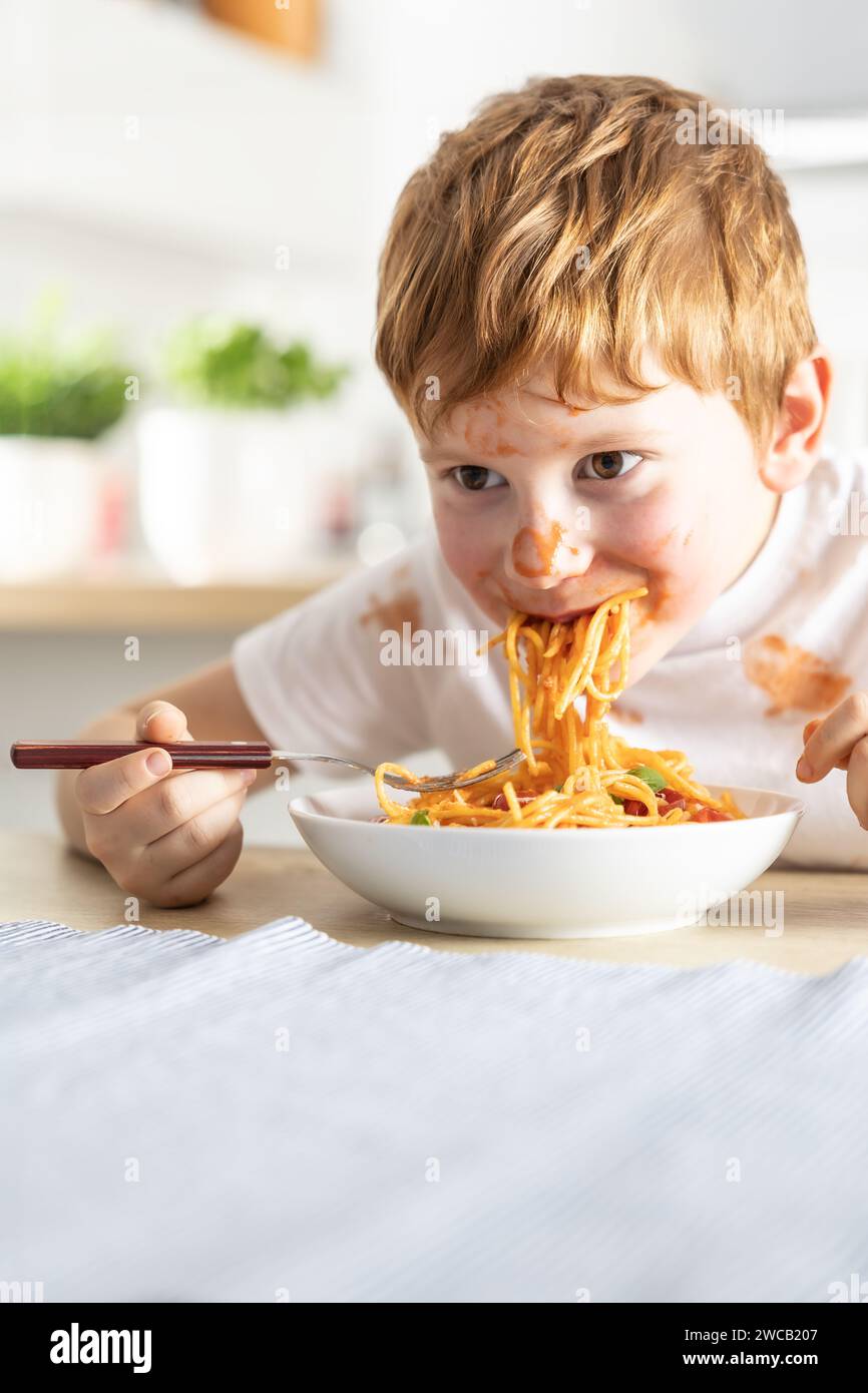 A cute little boy is eating spaghetti bolognese for lunch in the ...