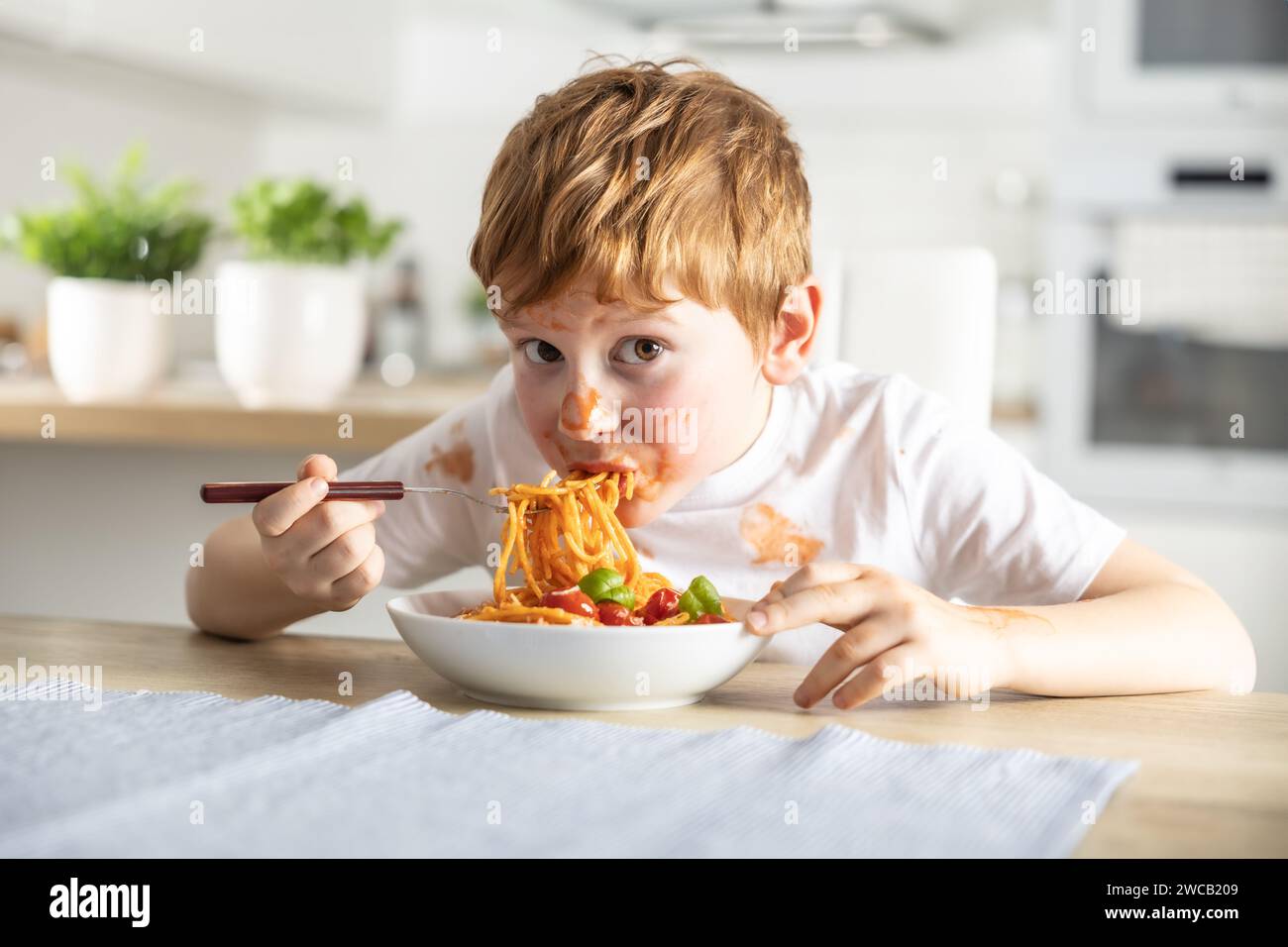 A cute little boy is eating spaghetti bolognese for lunch in the ...
