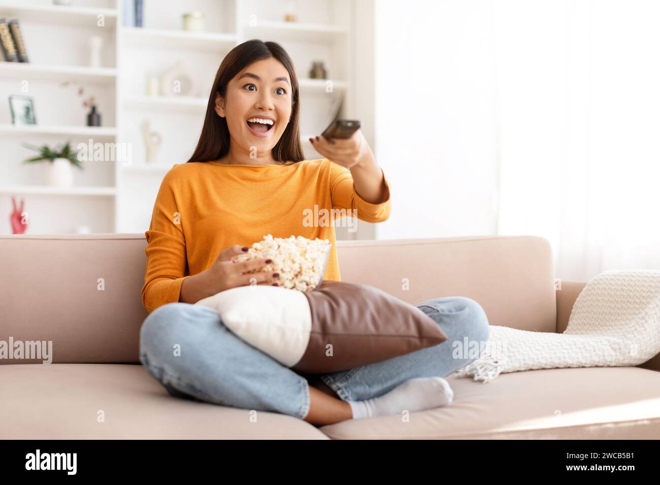 Excited young asian woman watching her favorite TV show Stock Photo