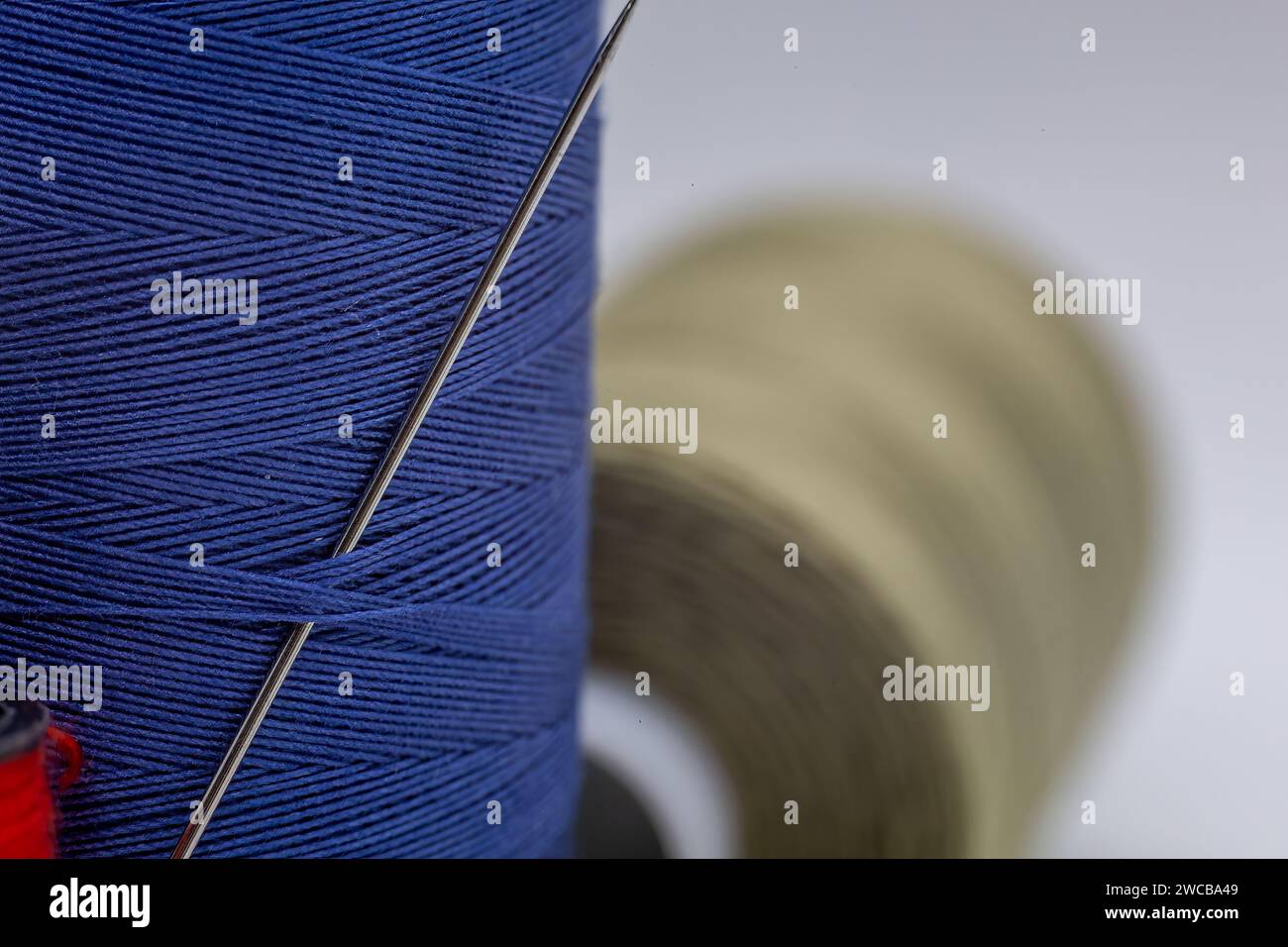 An image showcasing two spools of thread, one in a neutral color and the other in a vibrant shade of blue, positioned side by side Stock Photo