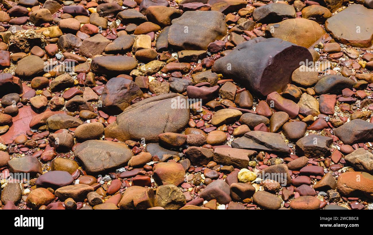 Pink stone texture and background. Close up of wet decorative stones. The Pink Coast or Lan Him Chomphu with sea background at Chanthaburi in Thailand Stock Photo