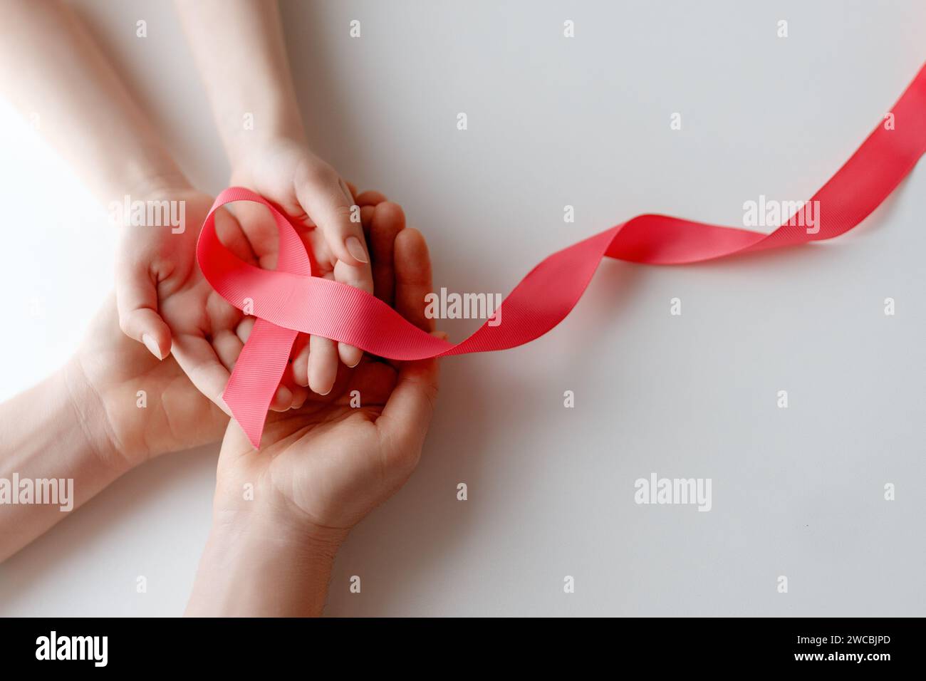 Hands of women with pink satin ribbon symbolizing concept of illness awareness, expressing solidarity and support for cancer patients and survivors. D Stock Photo