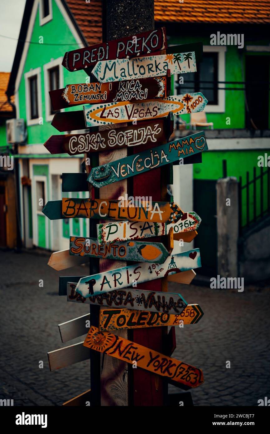 A street sign post in a bustling urban environment adorned with an array of directional signs. Stock Photo