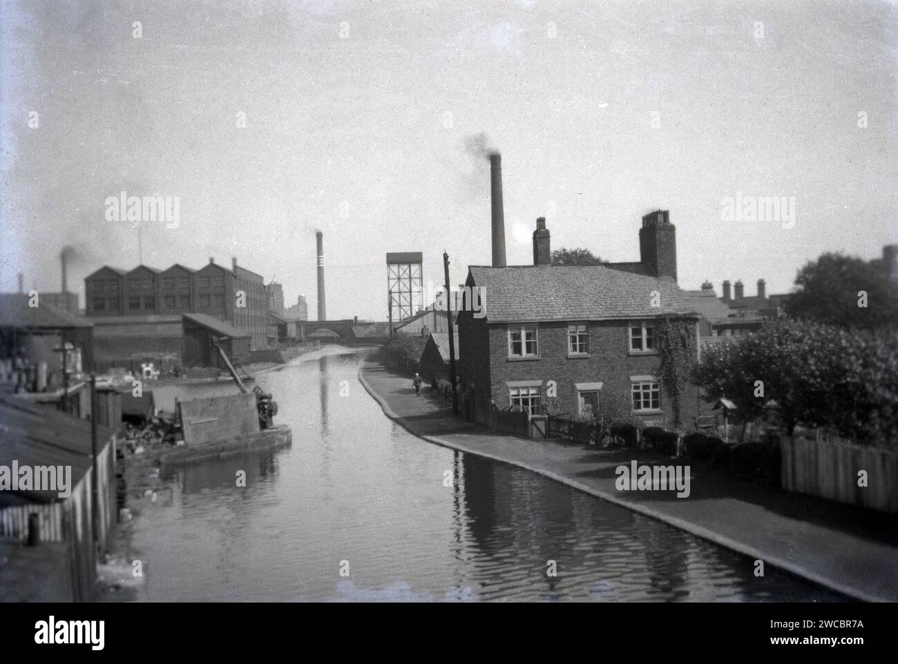 1941, historical, a view from this era of the Bridgewater Canal at Leigh, showing waterside buildings with several smoking chimneys. Opened in 1761, the waterway was built by the 3rd Duke of Bridgewater to transport coal from his mines in Worsley to Manchester and links Runcorn, Manchester and Leigh in North West England, UK. Stock Photo