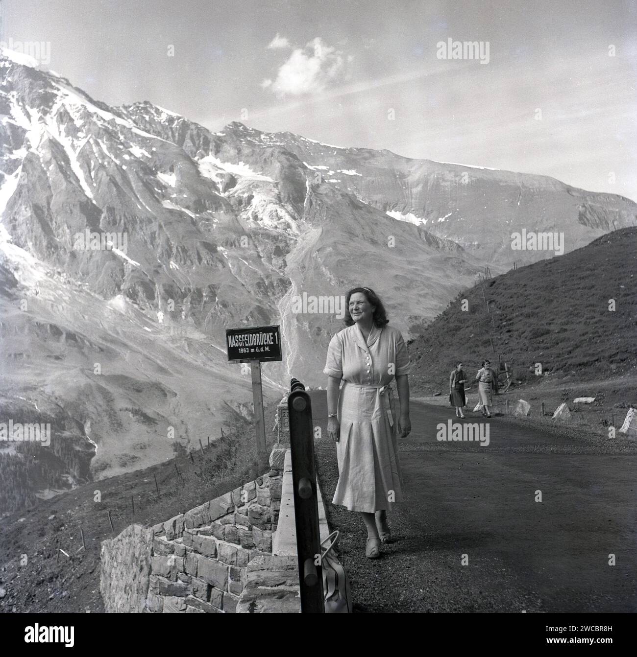 1950, historical, a lady walking along a high alpine road, Nassfeldbrucke 1 on the Austria-Germany border. Stock Photo