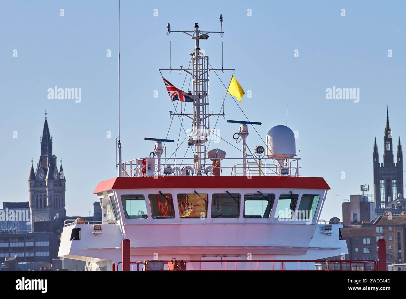 Flag of Britain waving on the ships mast in port, with buildings on the