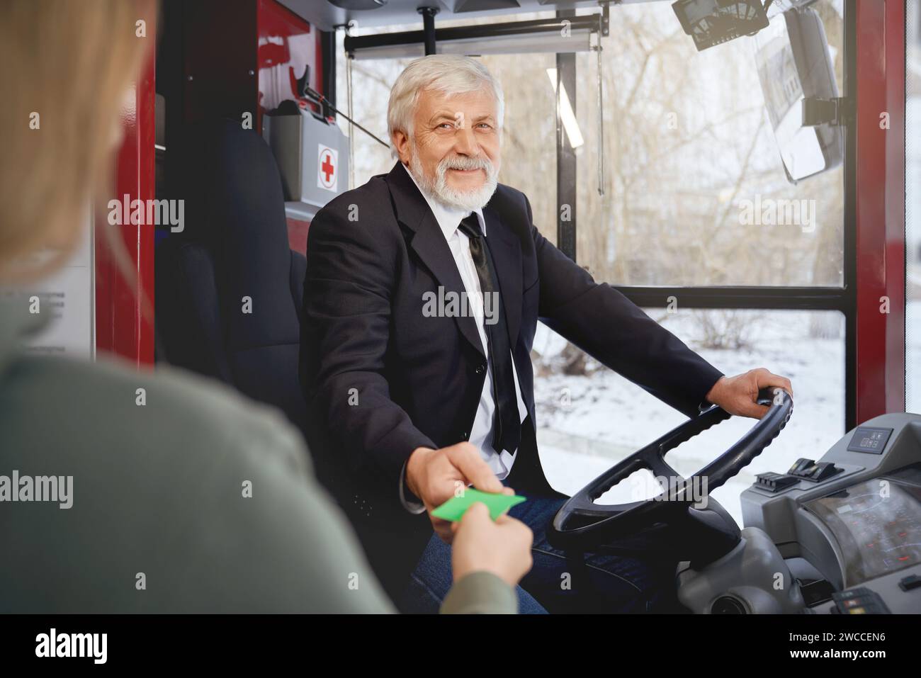 Front view of elderly smiling driver in black jacket holding ticket and ...
