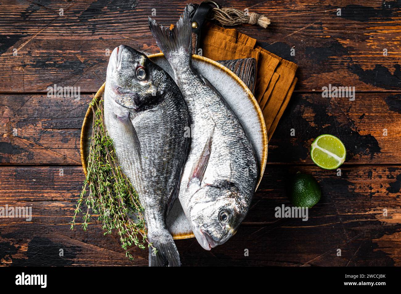 Fresh raw sea bream dorado fish with herbs. Black background. Top view ...
