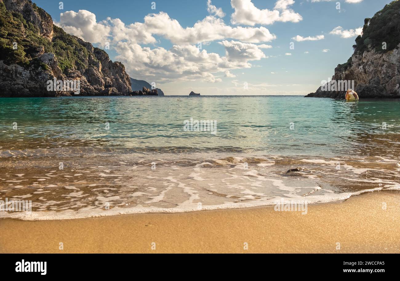The sandy beach of Agios Spiridom on the island of Corfu on a sunny day with blue sky with clouds. Amazing sandy beach with sea and clouds Stock Photo