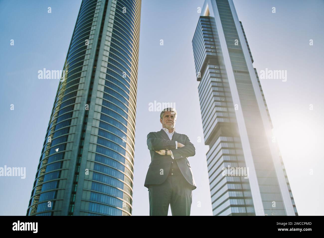 mature businessman with arms crossed and an office building in the ...