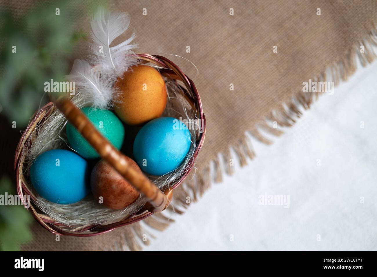Multi coloured Easter eggs in wicker basket on rustic background Stock Photo
