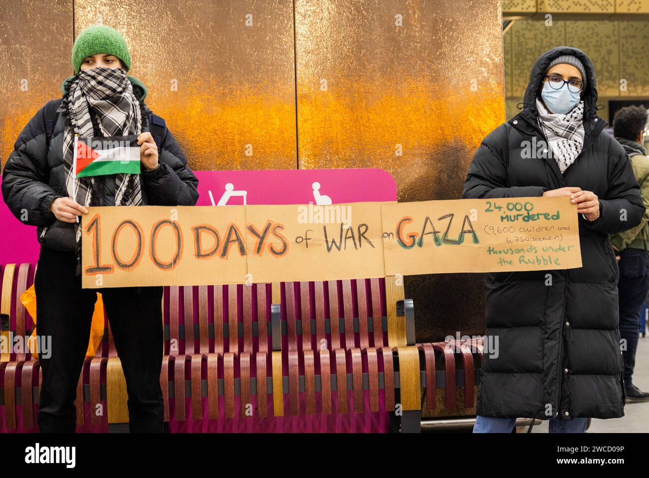 Leeds, UK. 15 JAN, 2023. Activists hold a sign stating '100 days of war in Gaza' at vigil in Leeds train station marking 100 days since the beginning of the current wave of Israeli action within Palestine.  Credit Milo Chandler/Alamy Live News Stock Photo