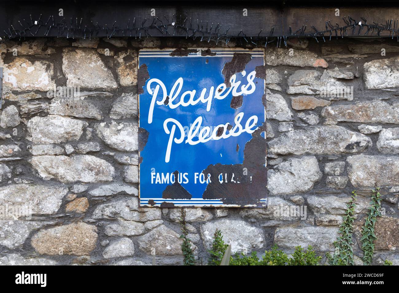 Old metal rusting advertising sign for Player's cigarettes, on wall, Rathdrum, Co. Wicklow, Ireland Stock Photo