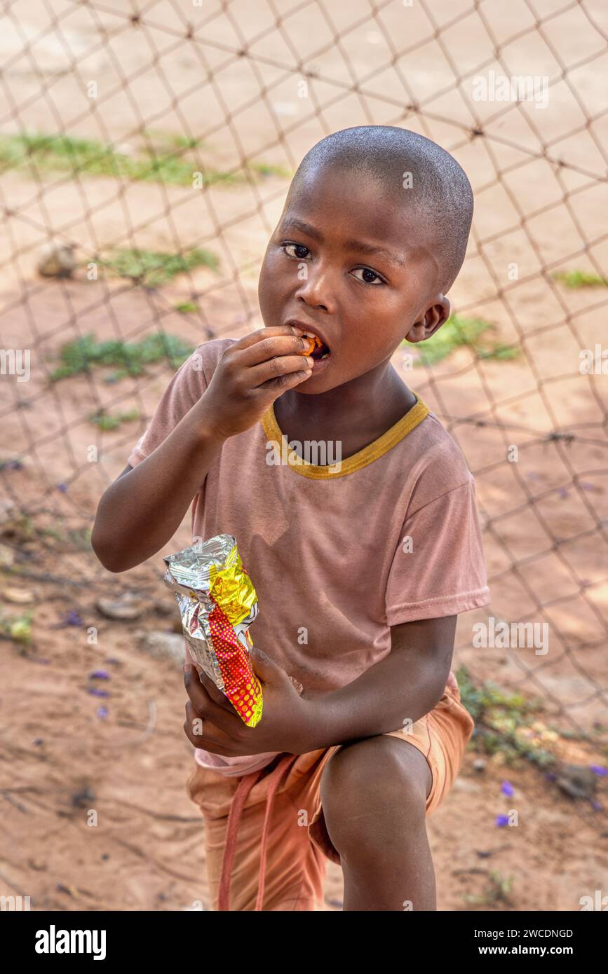 hungry african child in the village eating biscuits and maize snacks Stock Photo