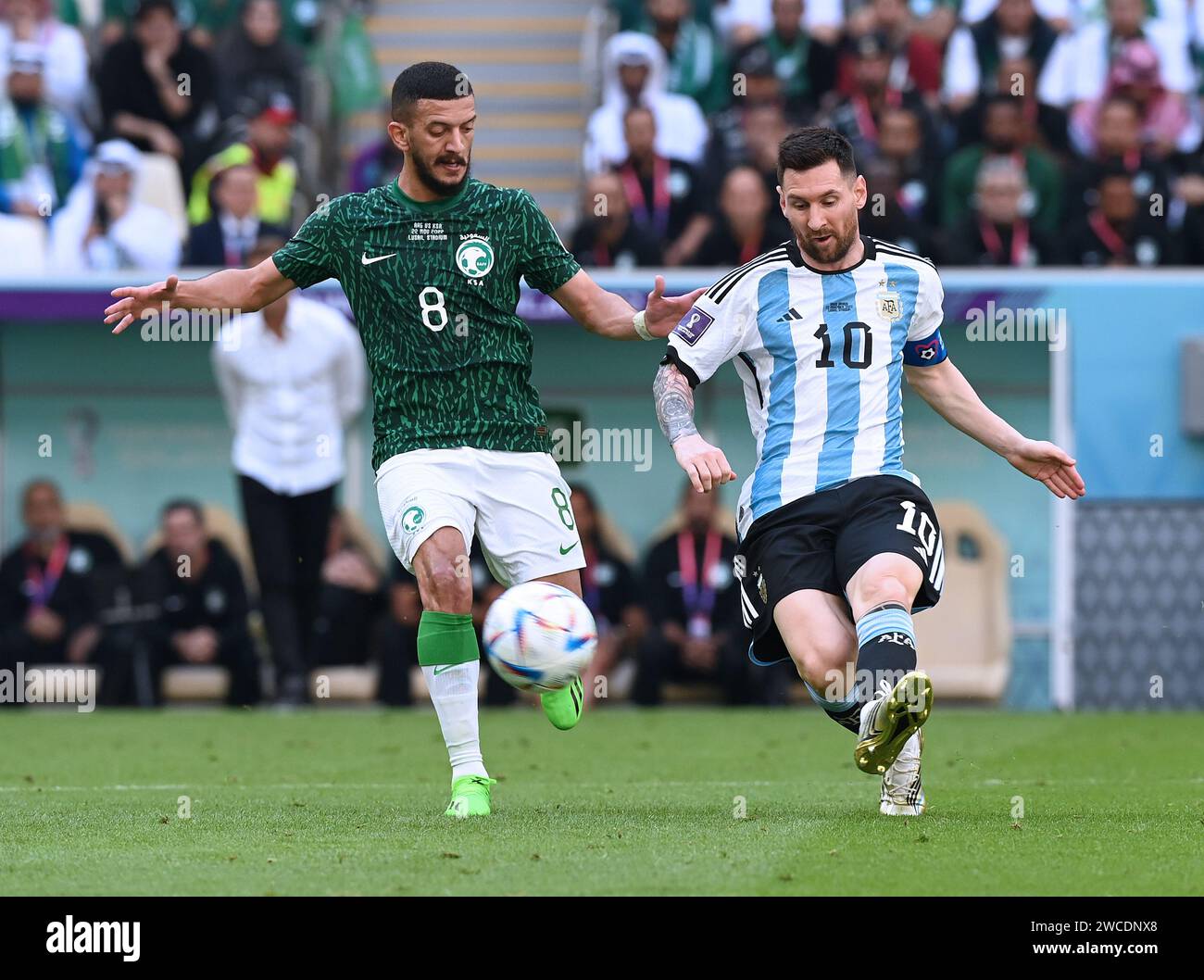 Lionel Messi passes the ball as Saudi Arabian defender, Abdulelah Al-Malki, presses hard to force an Argentina turnover during the 2022 FIFA World Cup Stock Photo