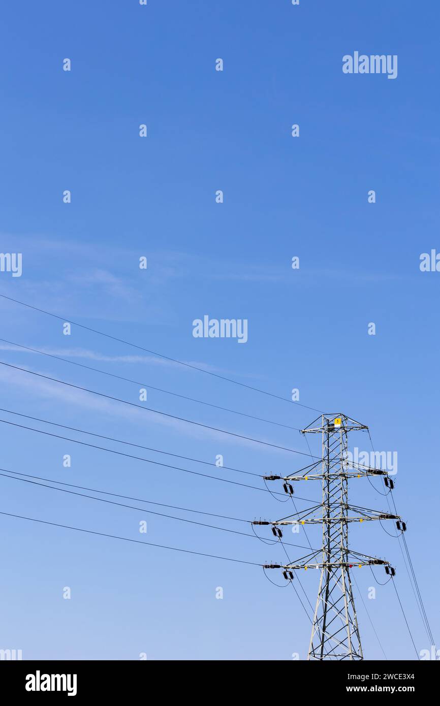 High voltage poles and high voltage cables against the background of the blue sky. Supply of electricity using overhead lines. Stock Photo