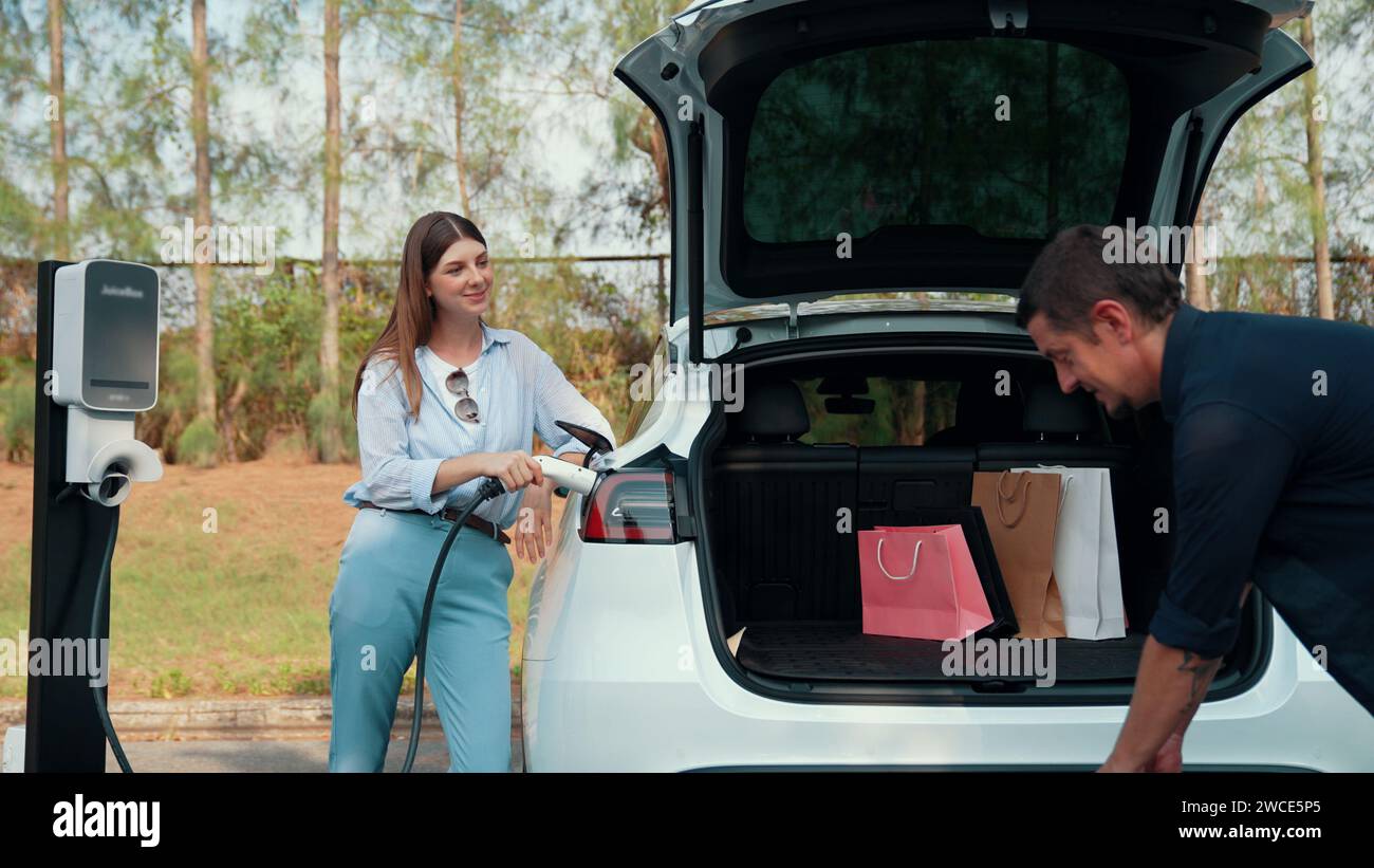 Couple recharge their EV car with electric battery charging station at ...