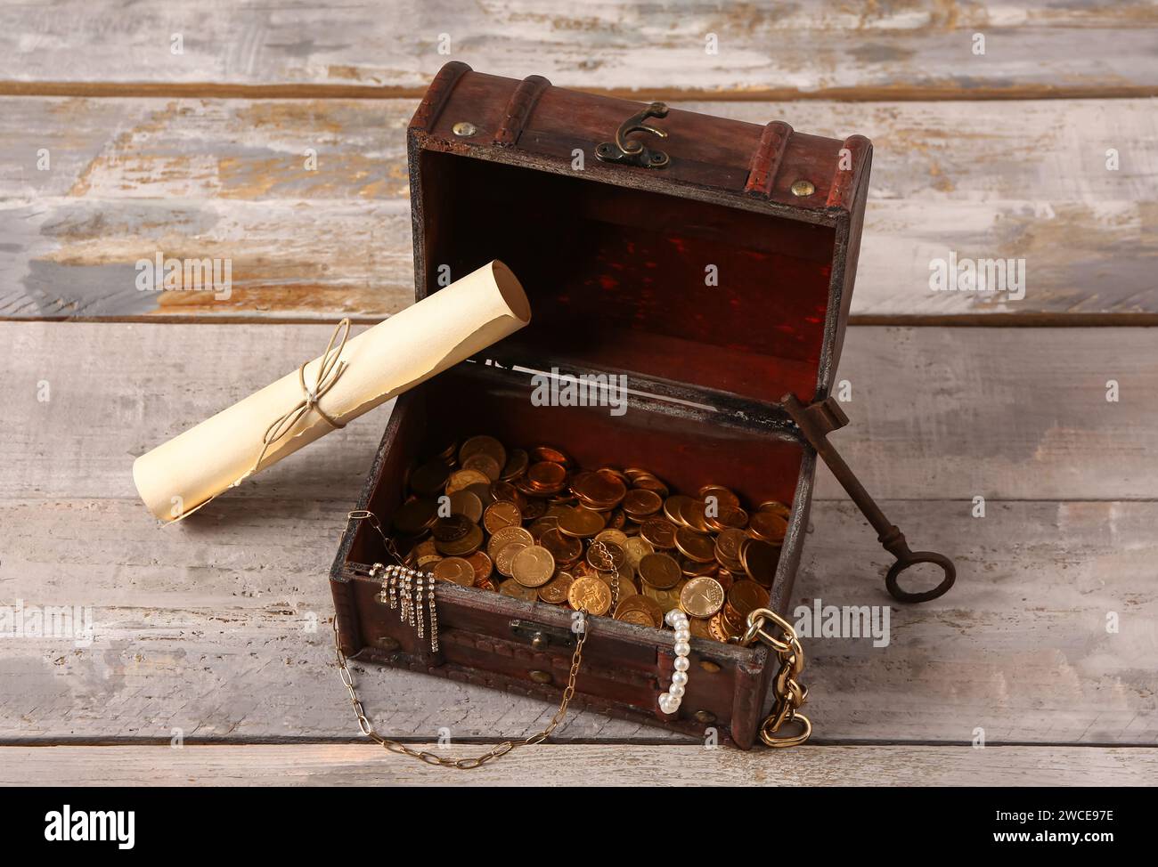 Old chest with treasures, key and map on light wooden background Stock