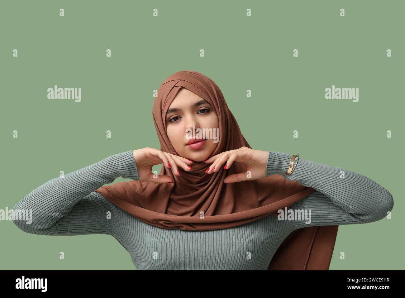 Beautiful young Muslim woman in hijab on green background Stock Photo ...