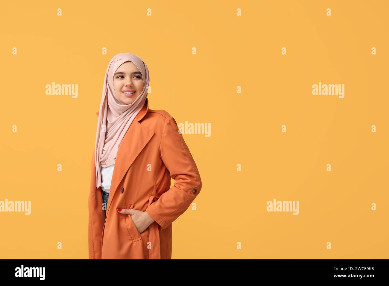 Happy young Muslim woman in hijab on yellow background Stock Photo - Alamy
