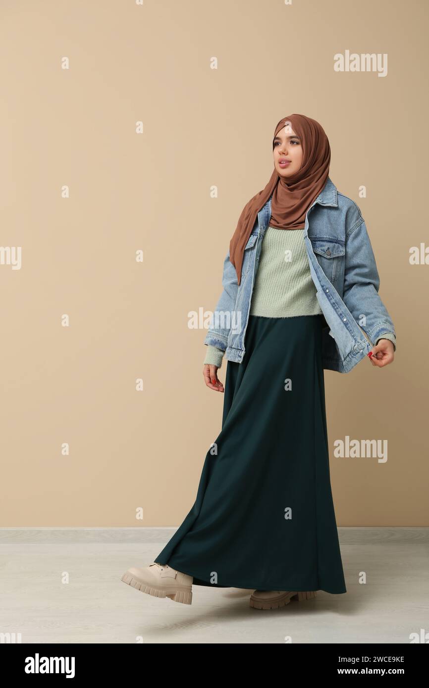 Beautiful young Muslim woman in hijab near beige wall Stock Photo - Alamy