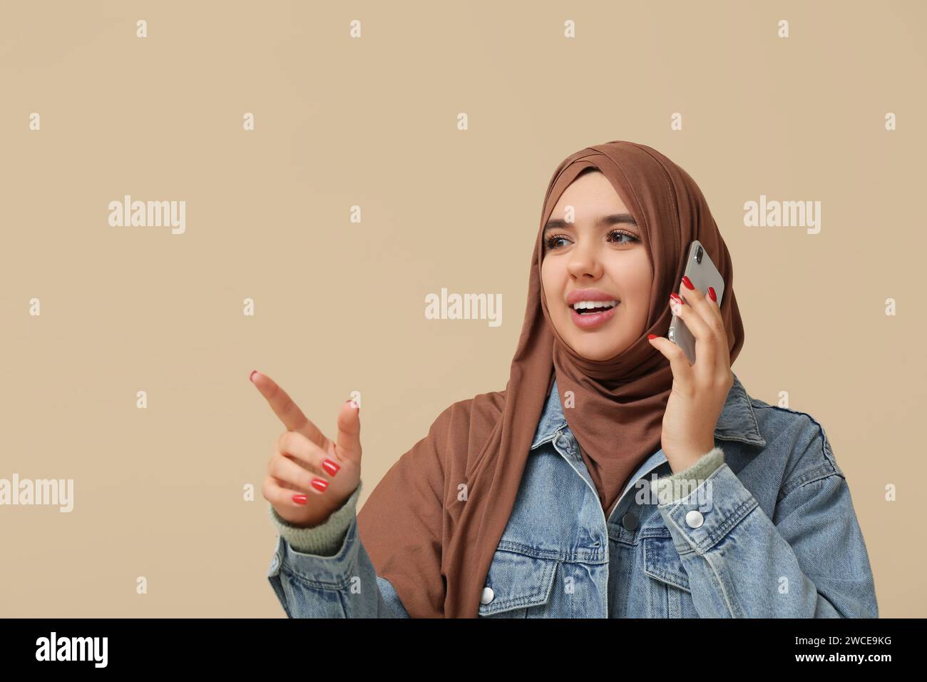 Beautiful young Muslim woman in hijab talking by mobile phone and ...