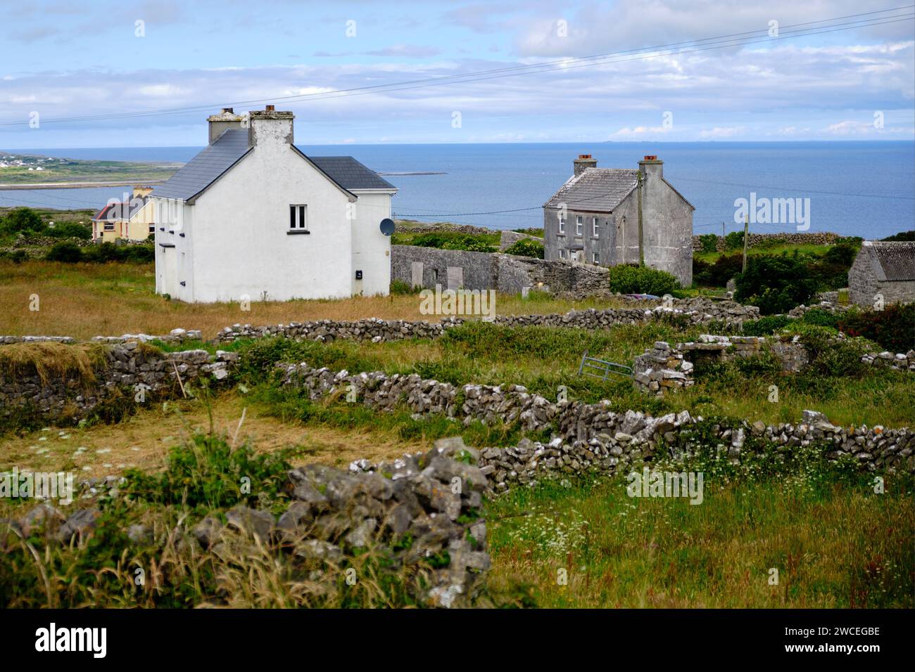 Irish country side scenery, with rock fences, little houses and ocean in background on Inishmore island Stock Photo