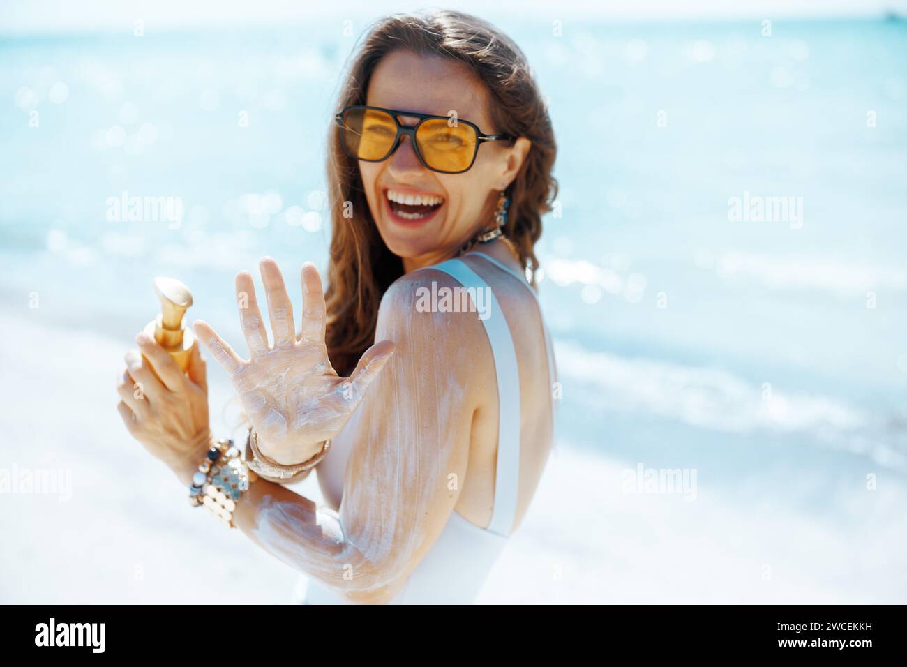 smiling stylish woman on the beach with spf. Stock Photo
